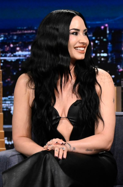 Demi Lovato sitting on Jimmy Fallon's set in a black dress